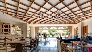 A spacious room with a high ceiling, patterned floor tiles, and a dining area with wooden furniture. - Sayang d’Amour (Seminyak)