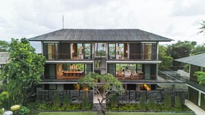 A modern two-story house with a balcony on each floor, surrounded by lush greenery. - Arnalaya Beach House (Canggu)