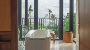 A bathroom with a bathtub, a small stool, and a woven basket. - Arnalaya Beach House (Canggu)