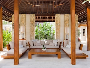 Relax in this open-plan living area with a high ceiling, surrounded by stone pillars and a central coffee table.