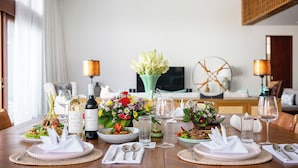 A dining table set for a meal with various dishes, wine bottles, and floral centerpieces. - Villa Indrani (Canggu)