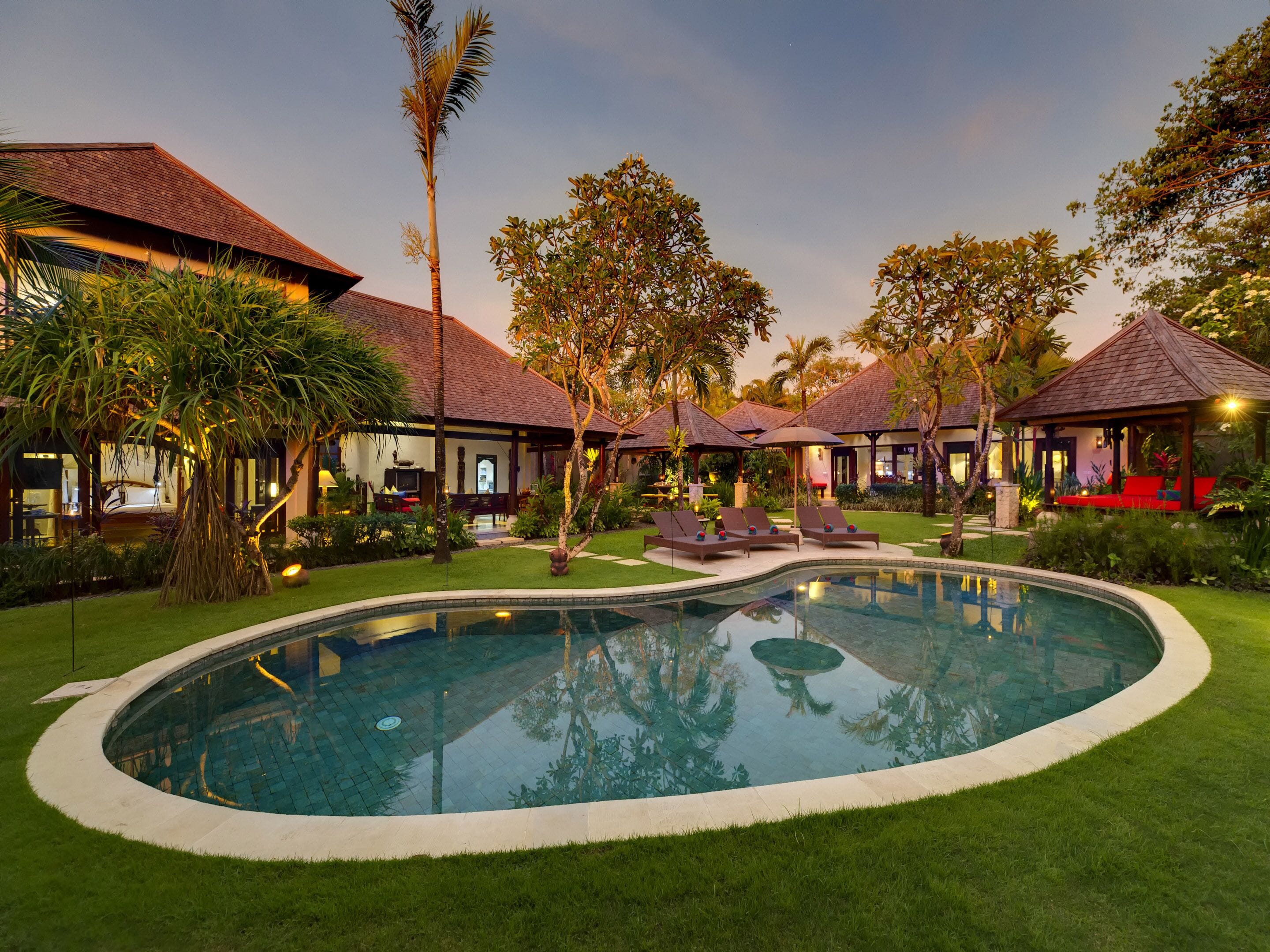Resort com piscina, espreguiçadeiras e paisagismo tropical.