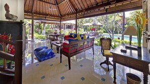A spacious lounge area with a high ceiling, a pool view, and a thatched roof structure. - Villa Kakatua (Canggu)