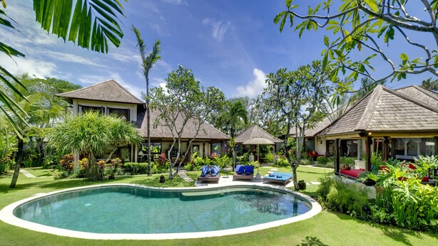 A resort with a swimming pool, lounge chairs, and tropical landscaping. - Villa Kakatua (Canggu)