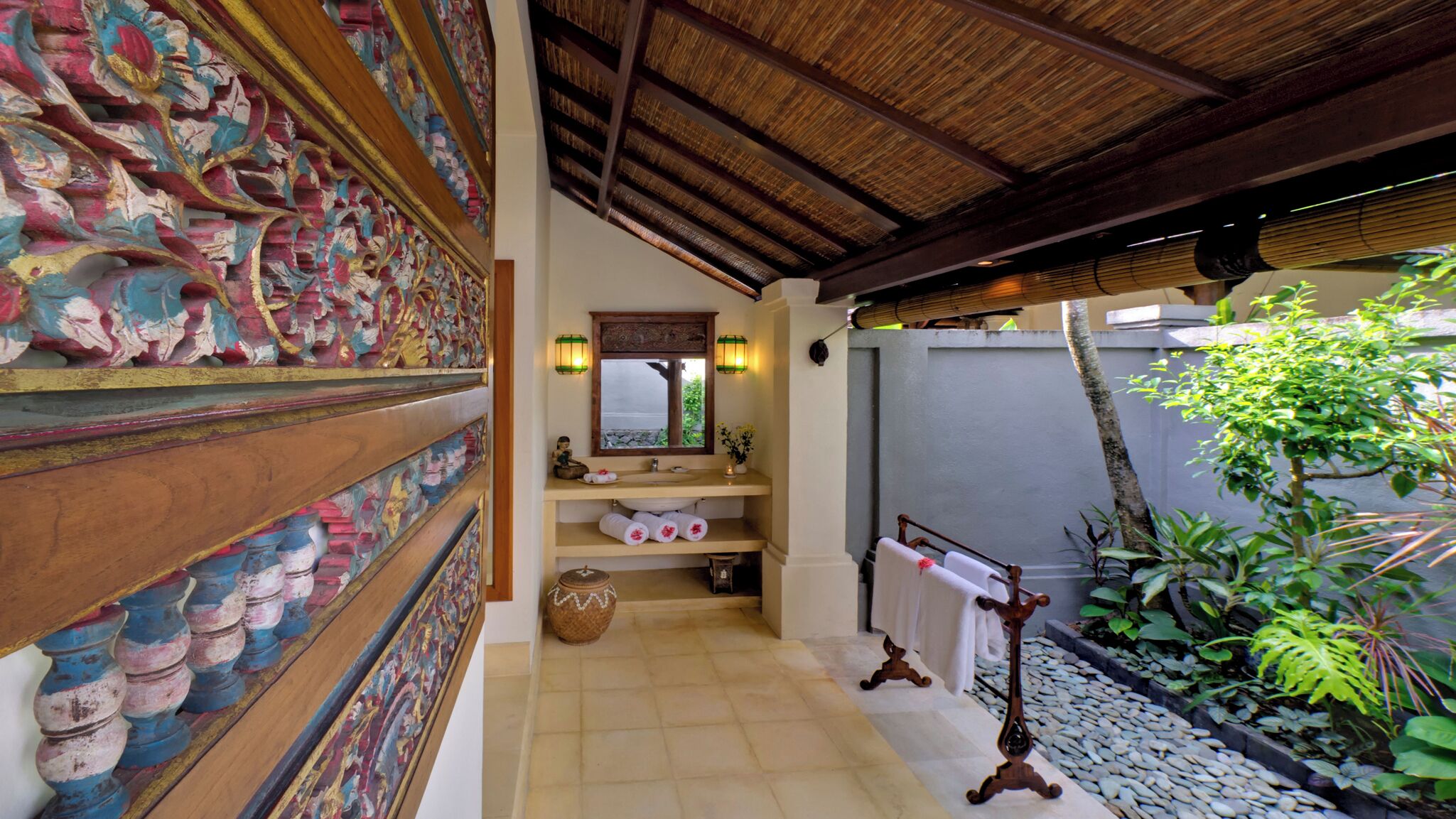 A bathroom with a tiled floor, a sink with a mirror, and a towel rack.