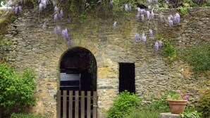 A stone building with an arched entrance, a wooden gate, and a small window. - Charming Riverside Cottage with Fishing & Wifi, Near Historic Sites (Rouez)