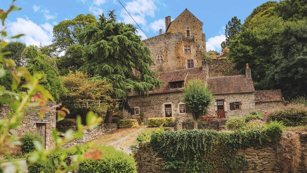 A stone building with a tower, surrounded by lush greenery and a stone wall. - Charming Riverside Cottage with Fishing & Wifi, Near Historic Sites (Rouez)