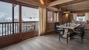 A spacious dining area with a wooden interior, large windows, and a view of a snowy landscape.