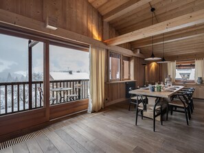Uma sala de jantar espaçosa com decoração em madeira, grandes janelas e vista para uma paisagem nevada.