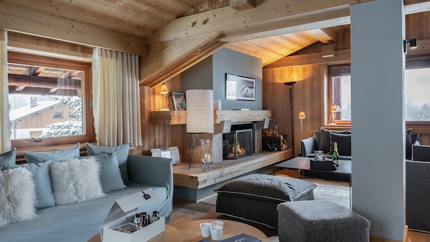 A cozy log cabin interior with a fireplace, a sofa, a coffee table, and a dining area.