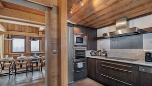 A modern kitchen with wooden beams, stainless steel appliances, and a granite countertop.