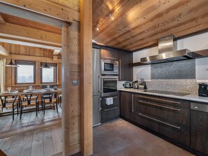 A modern kitchen with wooden beams, stainless steel appliances, and a granite countertop. - Chalet in Megève with wellness area and pets allowed (Megève)