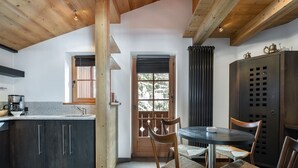A modern kitchen with dark cabinets, a wooden ceiling, and a dining area with a round table and woven chairs.