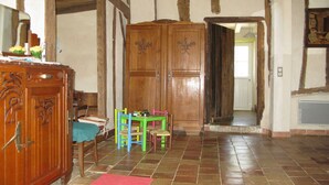 Een kamer met een houten garderobe, een rood tapijt en een tafel met kleurrijke stoelen.