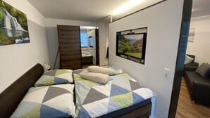 Ein Schlafzimmer mit einem Bett, einem Fernseher und einem Bild einer Wasserfall.