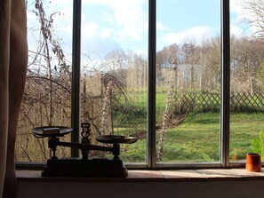 Enjoy a serene view of the garden from the large window, featuring a grassy area with trees and a wooden fence.