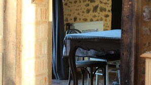 A rustic dining area with a wooden table and chairs, a brick wall, and a patterned wall in the background. - Bucolic Country House near Le Mans (Louplande)