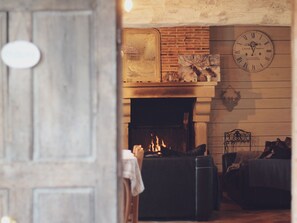 A cozy living room with a fireplace, a clock, and a rustic brick wall. - Bucolic Country House near Le Mans (Louplande)
