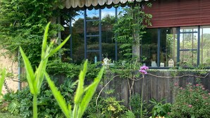 A garden with a wooden fence, various plants, and a small house with a window. - Bucolic Country House near Le Mans (Louplande)