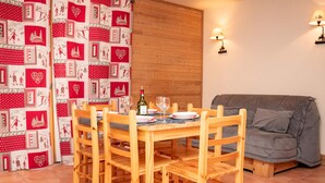 Un comedor con mesa y sillas de madera, un sofá gris y una cortina estampada.