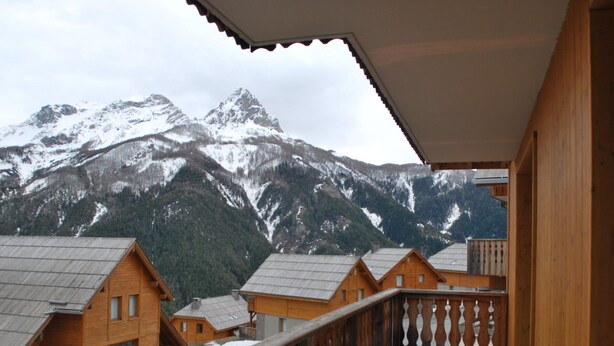 Un chalet de madera con balcón que da a montañas nevadas.