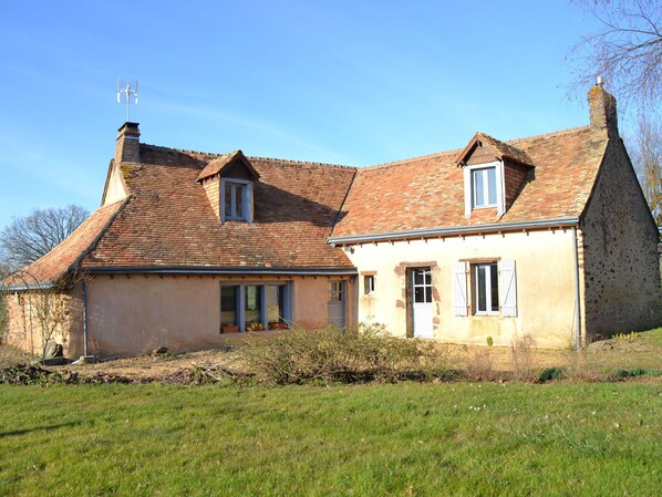 A two-story house with a sloped roof, a chimney, and a small window.