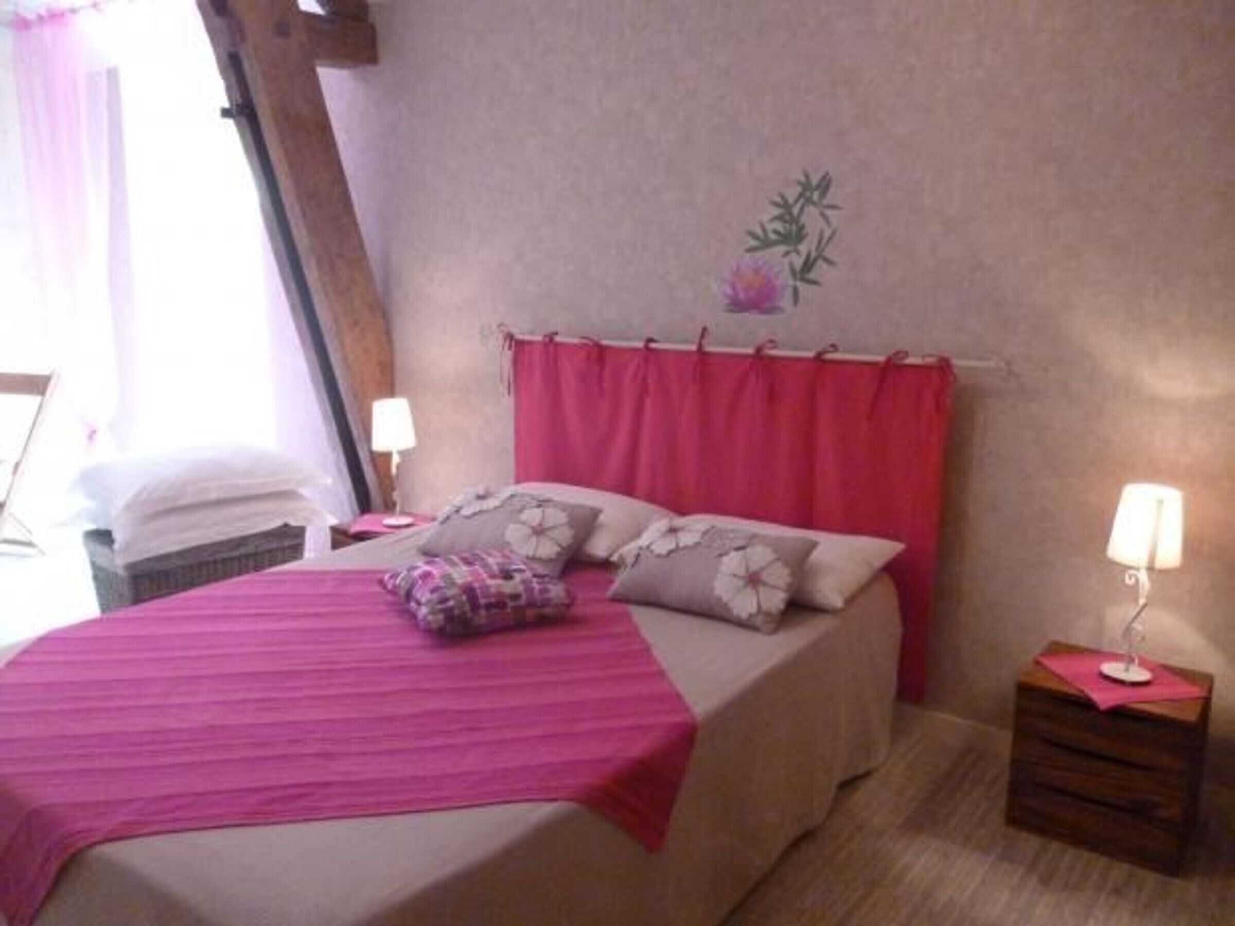Une chambre à coucher avec un lit, des oreillers, une table de chevet, une lampe et un élément décoratif mural.