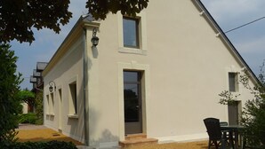 Ein modernes, zweistöckiges Haus mit überdachter Terrasse, einem kleinen Garten und einem Essbereich.