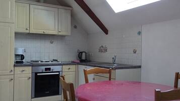 A kitchen with a dining table, cabinets, a Bosch oven, a coffee maker, and a skylight.