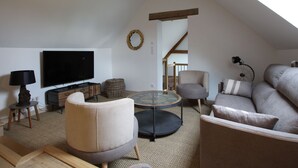 A modern living room with a television, sofas, a coffee table, and a staircase leading to an upper level.