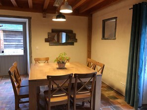 Comedor con mesa de madera, seis sillas, una planta en maceta e iluminación colgante.
