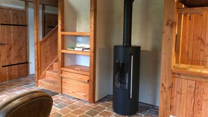 Un intérieur en bois avec une cheminée, un escalier et un fauteuil.