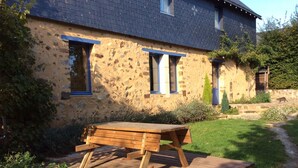 Un bâtiment rustique en pierre, avec une table de pique-nique en bois devant.