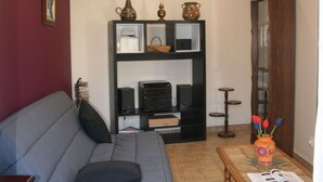 A living room with a grey sofa, a black entertainment unit, and a wooden cabinet. - Spacieuse maison confortable avec jardin, à 20 min du centre-ville et proche du circuit des 24H du Mans (Le Mans)