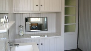 A bathroom with white cabinetry, a mirror, a sink, and a door with frosted glass panels. - Spacieuse maison confortable avec jardin, à 20 min du centre-ville et proche du circuit des 24H du Mans (Le Mans)