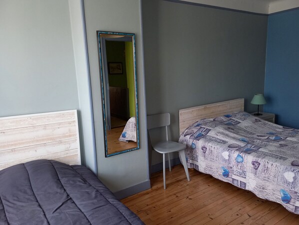 Un dormitorio con cama, una silla, una mesita de noche, una lámpara y un espejo.