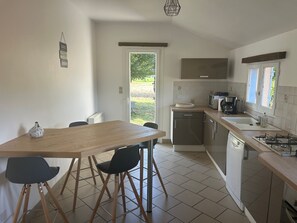 Eine moderne Küche mit Essbereich, ausgestattet mit einem Holztisch, Stühlen, einer Mikrowelle und einem Spülbecken.
