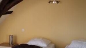 A cozy room with a sloped ceiling, a bed with white bedding, and a small bedside table. - Charming Cottage: 3BR, Cozy Fireplace, Large Garden, Near Bercé Forest (Saint-Mars-d'Outillé)
