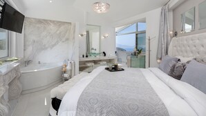 A modern bedroom with a large bed, a bathtub, and a vanity. - Dion  Villa with Pool in Zakynthos Greece (Zakynthos)