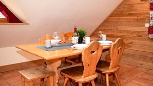 Ein Essbereich mit einem Holztisch, gedeckt für vier Personen, inklusive Weingläsern, Tellern und einer Kerze.