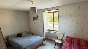 A bedroom with a bed, a chair, a window with curtains, a radiator, and a picture on the wall. - Charming Country House with Garden, Terrace, Petanque & Fireplace Near Vernie (Vernie)