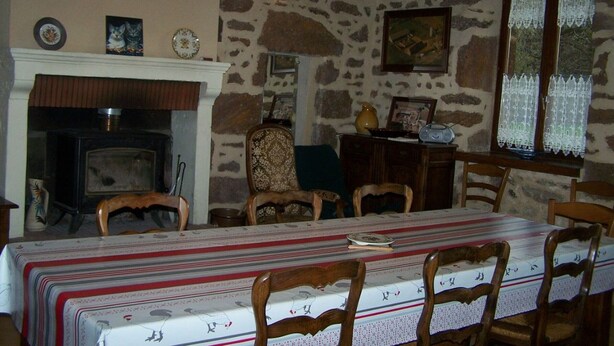 A rustic dining room with a stone wall, wooden beams, a fireplace, and a table set for four. - Charming Country House with Garden, Terrace, Petanque & Fireplace Near Vernie (Vernie)