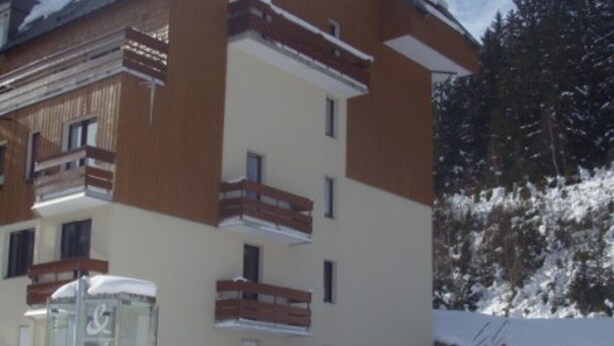 A multi-story building with balconies, a glass elevator, and a snow-covered ground.
