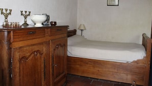 A room with a wooden bed, a dresser with drawers, a lamp, and two framed pictures on the wall.