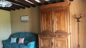 Une pièce avec un meuble en bois, un canapé de couleur turquoise et un porte-manteau.