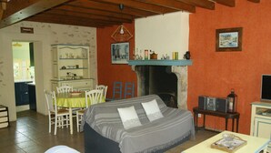 Ein gemütliches Zimmer mit einem Bett, einem Esstisch mit Stühlen, einem Kamin und einem Fernseher.