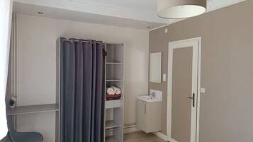 Een kamer met een bureau, een stoel, een kledingkast, een spiegel en een wastafel.