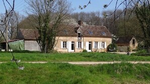 Une maison à deux étages, avec un toit en pente, des volets blancs et un petit porche.