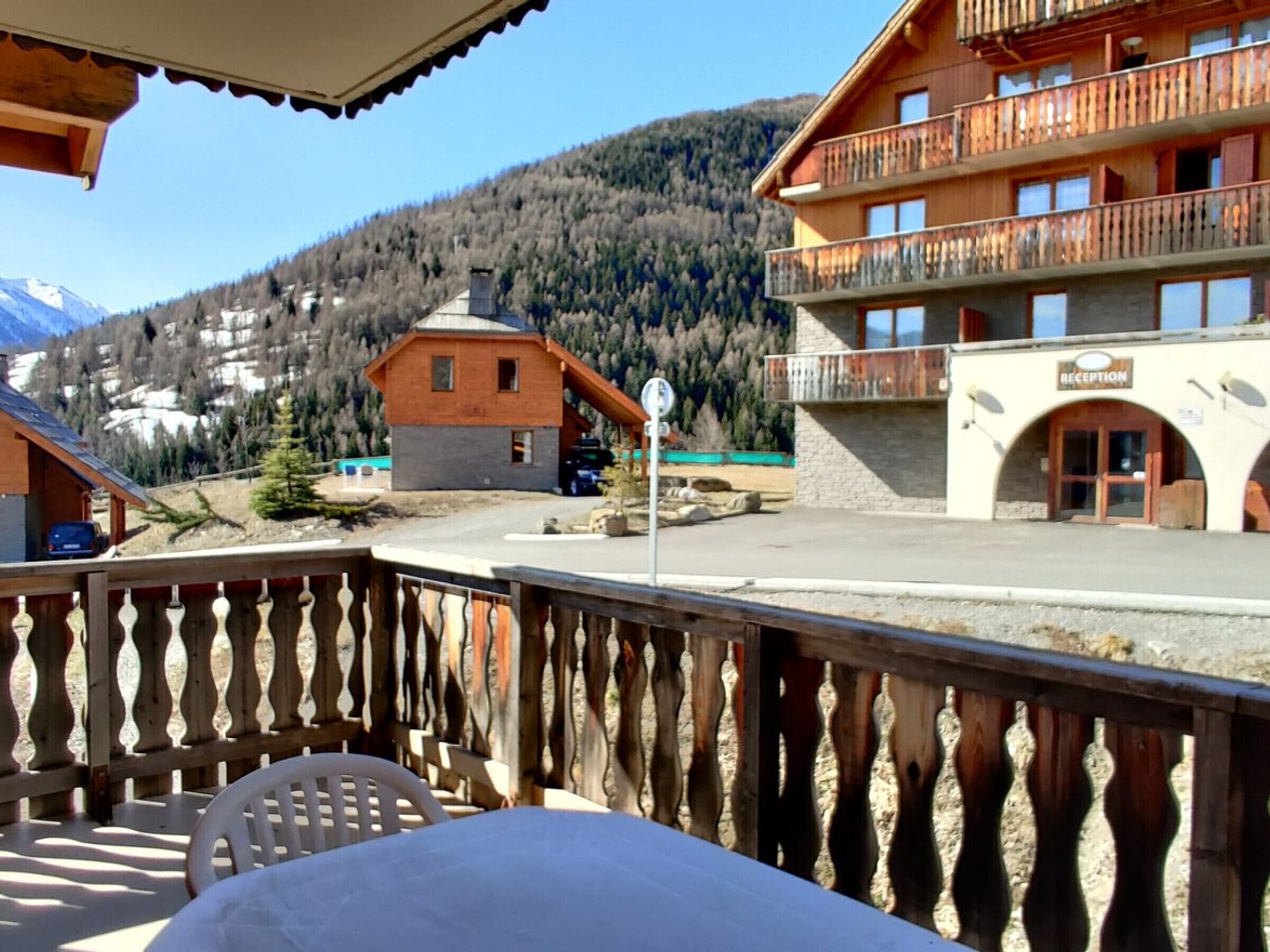Un edificio in legno con area receptione, un balcone con ringhiera e uno sfondo montuoso.