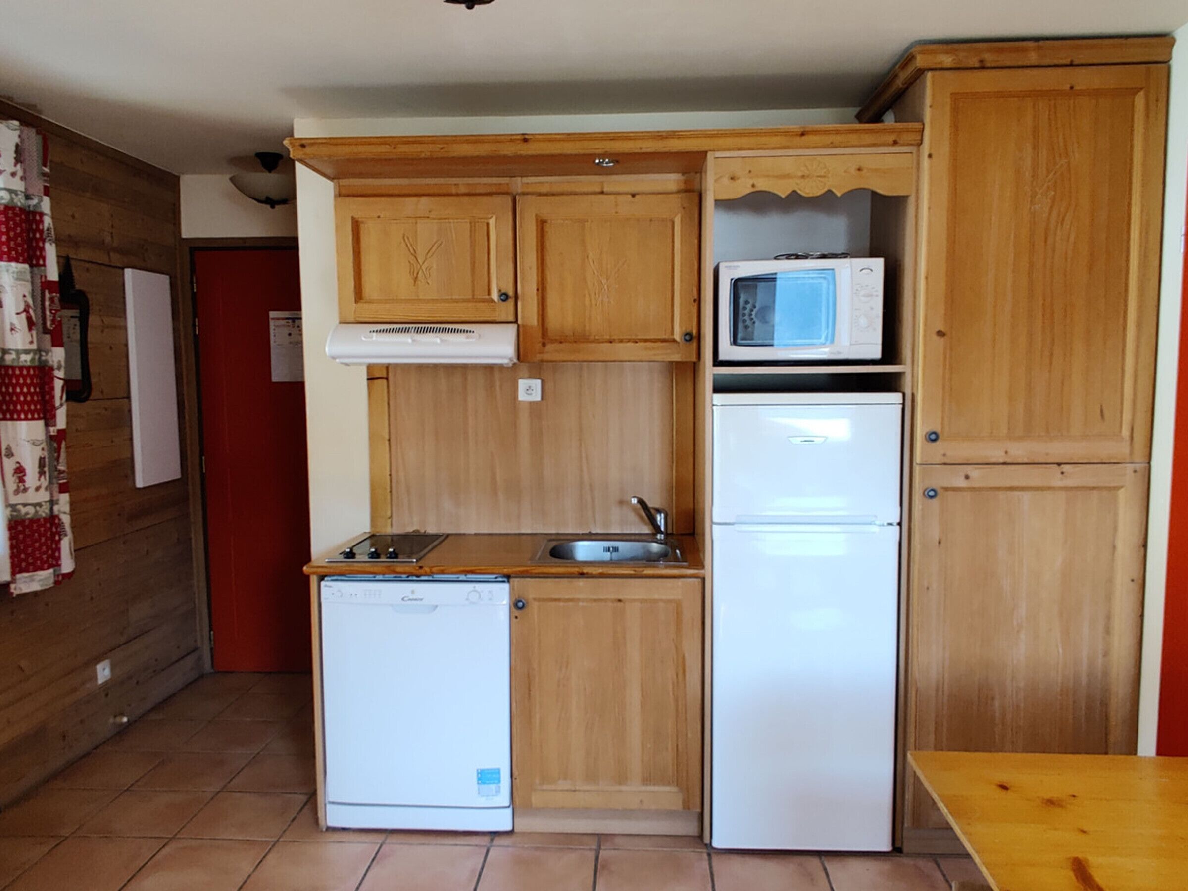 Una cucina compatta con mobili in legno, un forno a microonde, una lavastoviglie e un lavello.